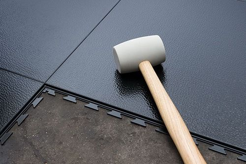 Installing interlocking floor tiles with rubber mallet tool
