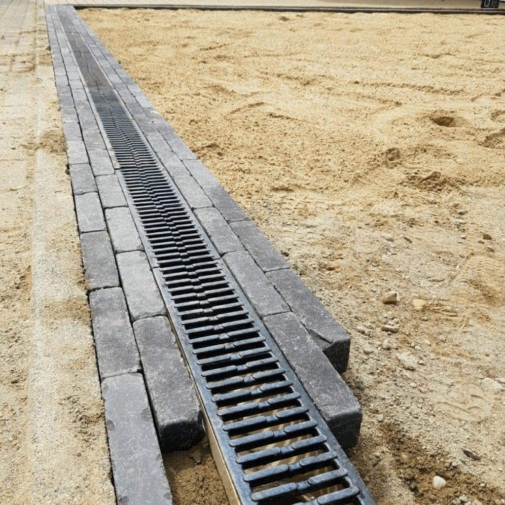 Linear drainage system installed between paving stones and sand base