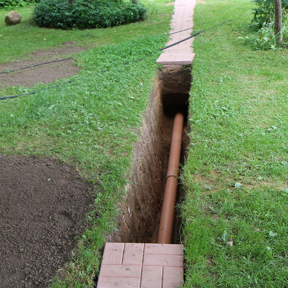 Underground drainage pipe installation in garden trench with cover